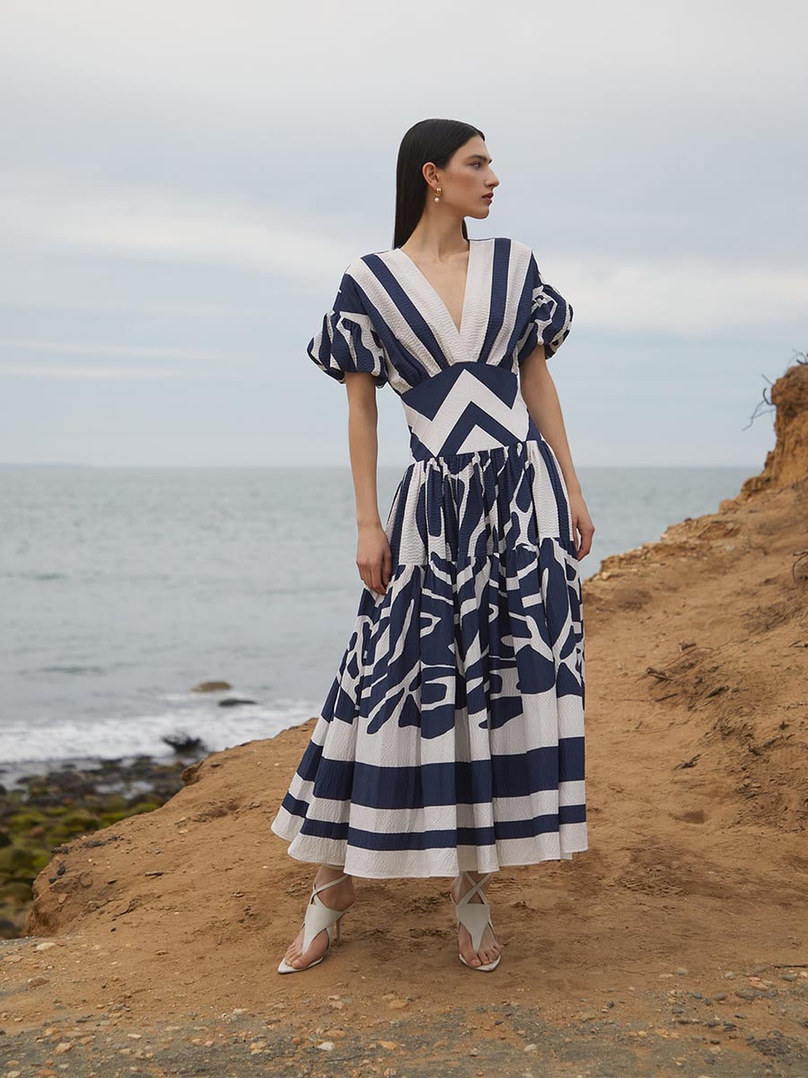 Navy and white graphic print on a full-skirted midi dress, shot on a coastal cliff